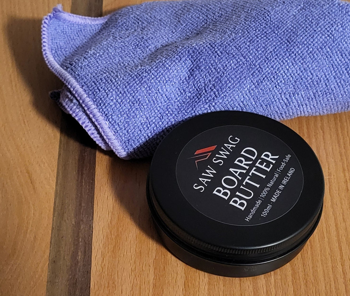 Container of beard butter with a blue towel on a wooden surface