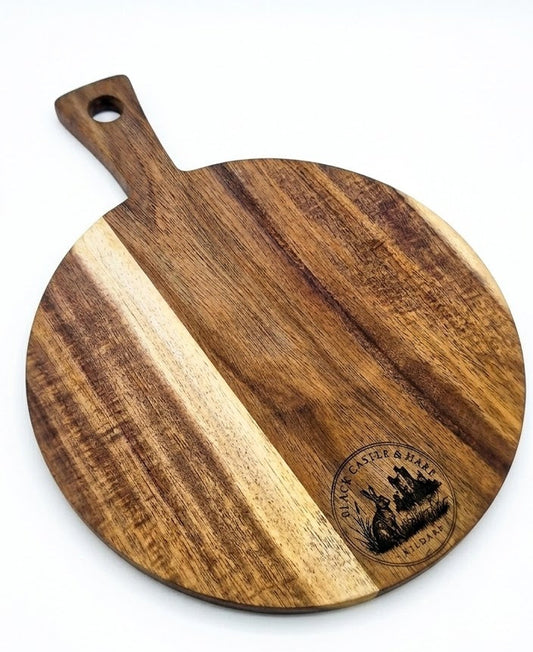 Round 300mm acacia pizza and charcuterie board with 100mm handle double oiled by Black Castle & Hare Kildare on white background