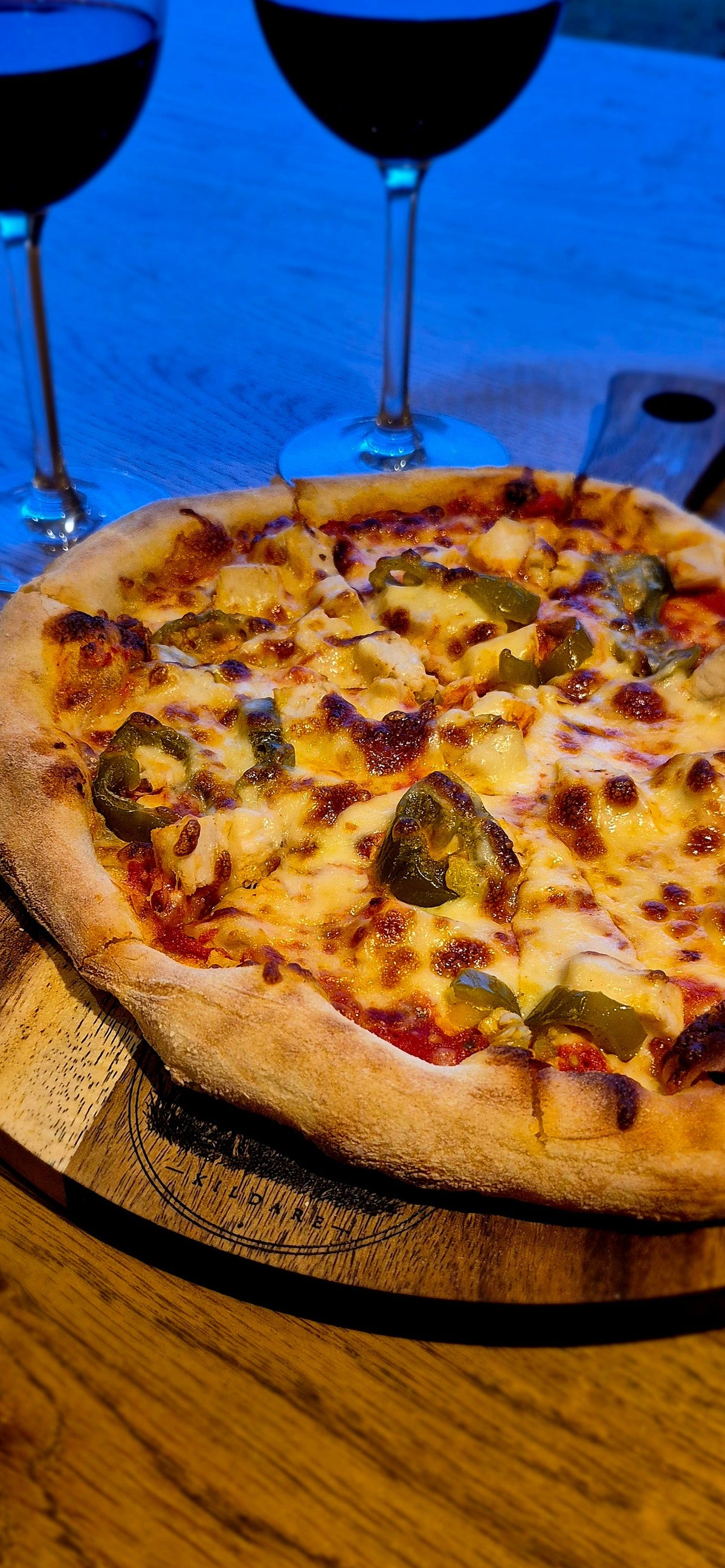 Close-up of gourmet pizza served on a food-safe double-oiled 300mm round acacia wooden board by Black Castle & Hare Kildare