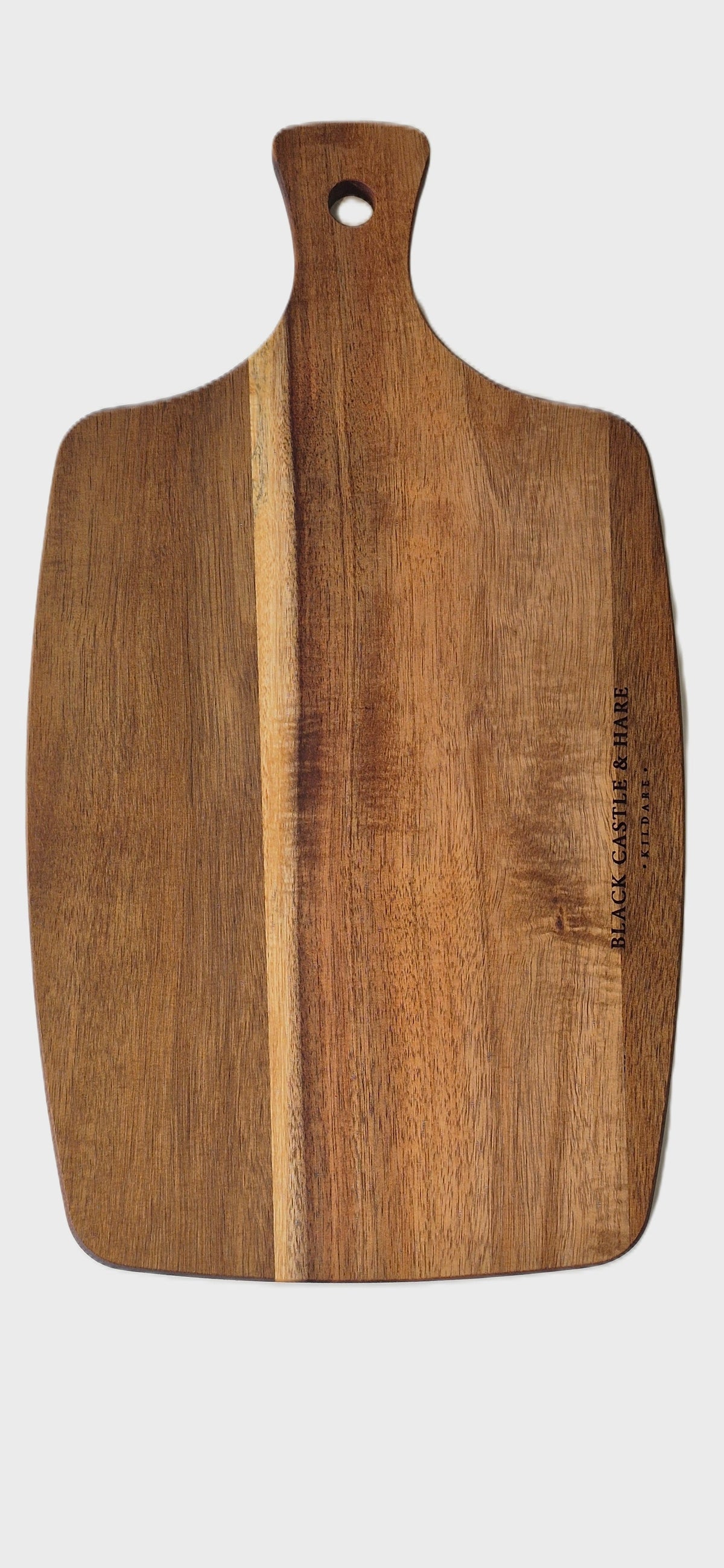 A rectangular wooden cutting board with a rounded handle and a hole at the top, featuring a natural wood grain pattern and a small brand engraving on the right side, shown against a white background.