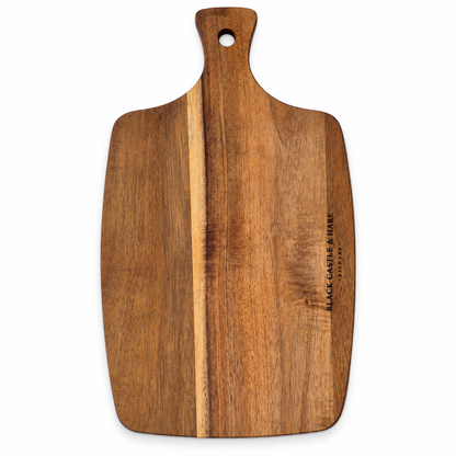 A rectangular wooden cutting board with a rounded handle and a hole at the top, featuring a vertical lighter wood stripe down the center and the brand name 'Black Castle & Fine' engraved on the right side, shown on a plain white background.