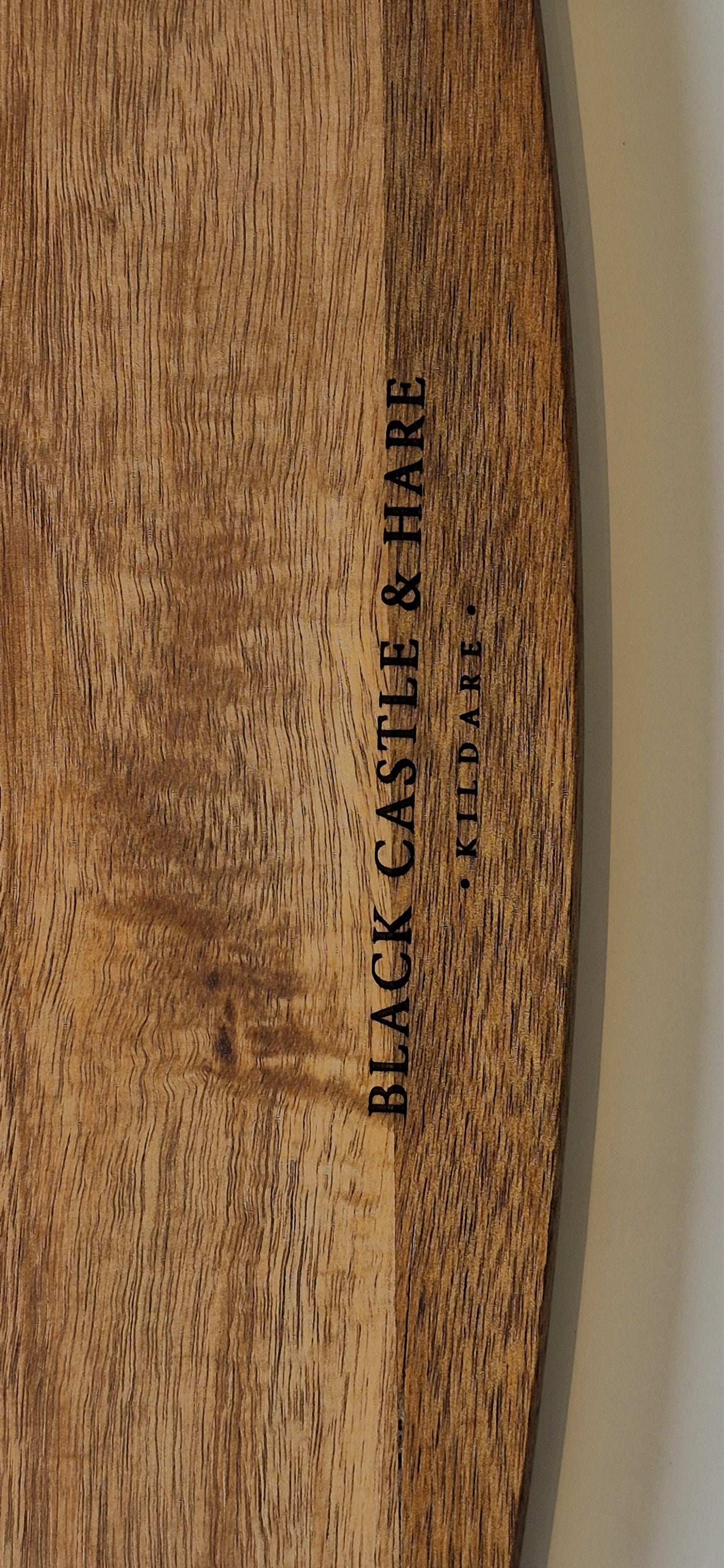 Close-up of a wooden surface with vertical black text reading 'BLACK CASTLE & HARE' and smaller text 'Kildare' beside it.