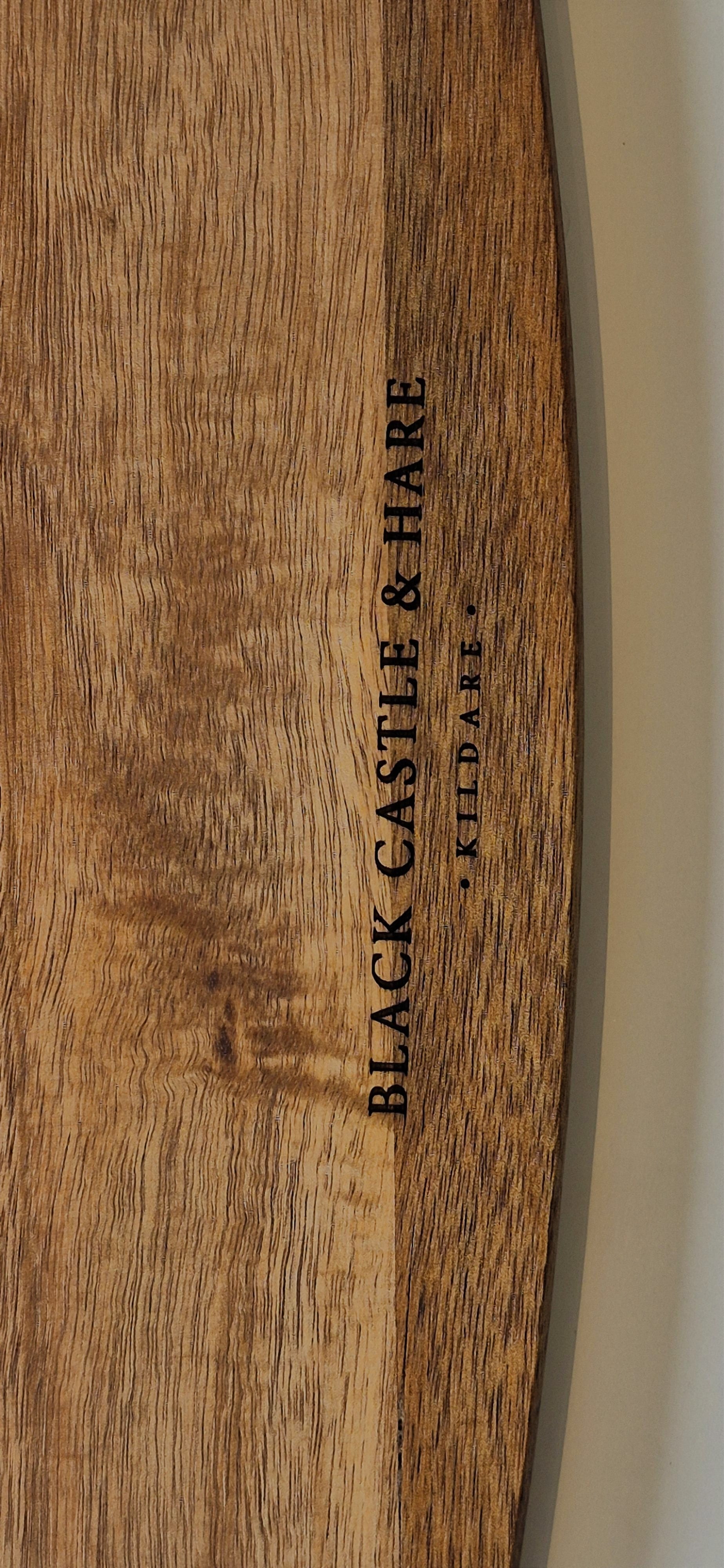 Close-up of a wooden surface with vertical black text reading 'BLACK CASTLE & HARE' and smaller text 'Kildare' beside it.