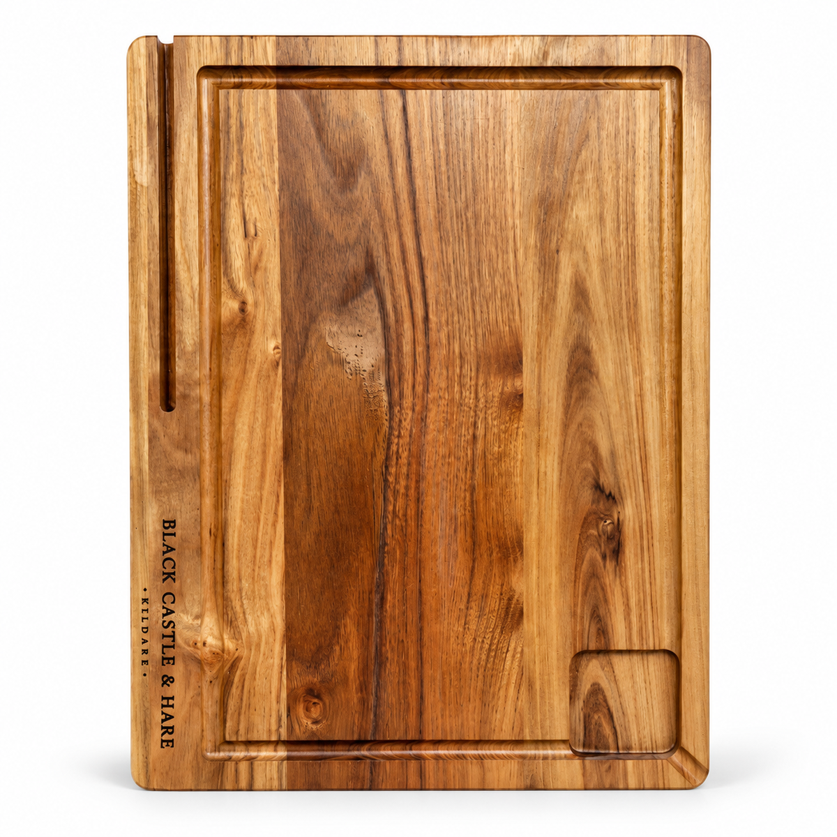 A rectangular wooden serving board with a warm medium-brown wood grain, featuring a raised rim, a vertical slot on the left edge, and the brand name 'BLACK CASTLE & HARE' printed vertically on the left side. A small recessed slot is also present in the bottom right corner.