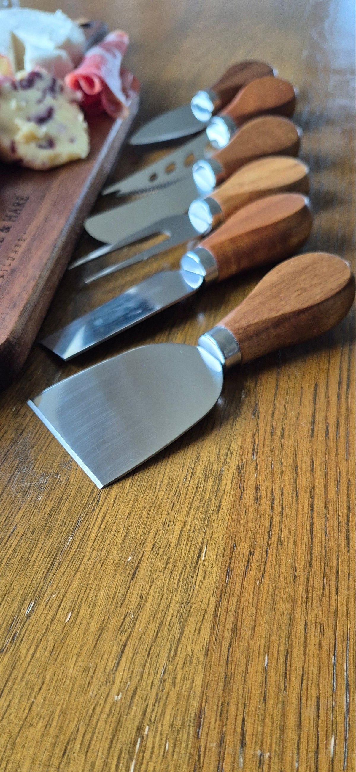 Close-up detail of the durable blades and ergonomic handles on a 6-piece premium cheese and meat knife set for artisan chopping boards.