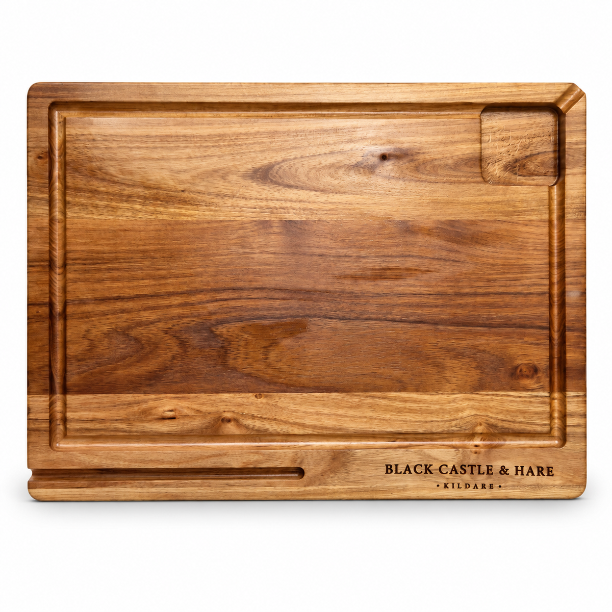 A rectangular wooden cutting board with a rich brown wood grain, featuring a recessed handle slot at the bottom, a small cutout in the top right, and the engraved brand name 'BLACK CASTLE & HARE' on the bottom right, set against a plain white background.