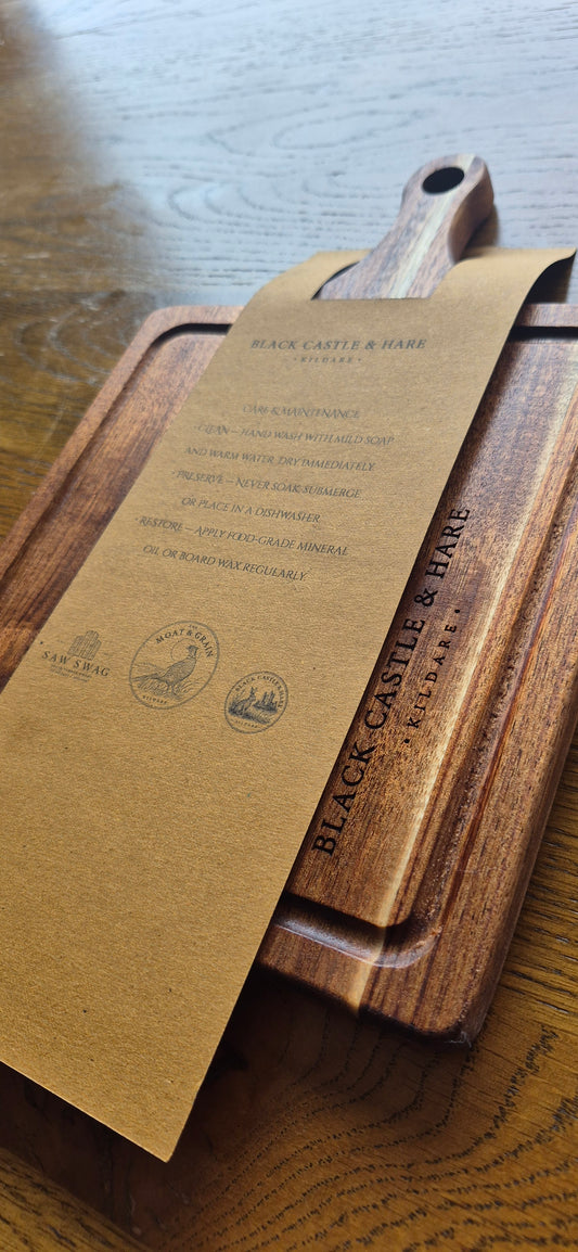 Close-up of the integrated juice groove and handle on a 15mm thick double-oiled wooden chopping board with a care card by small business Black Castle & Hare.