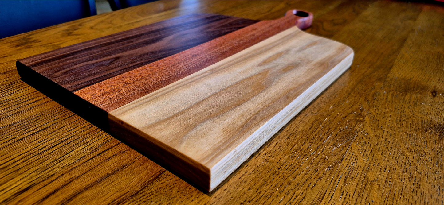 Close-up of the minimalist integrated handle on a dark hardwood serving board, showing smooth craftsmanship