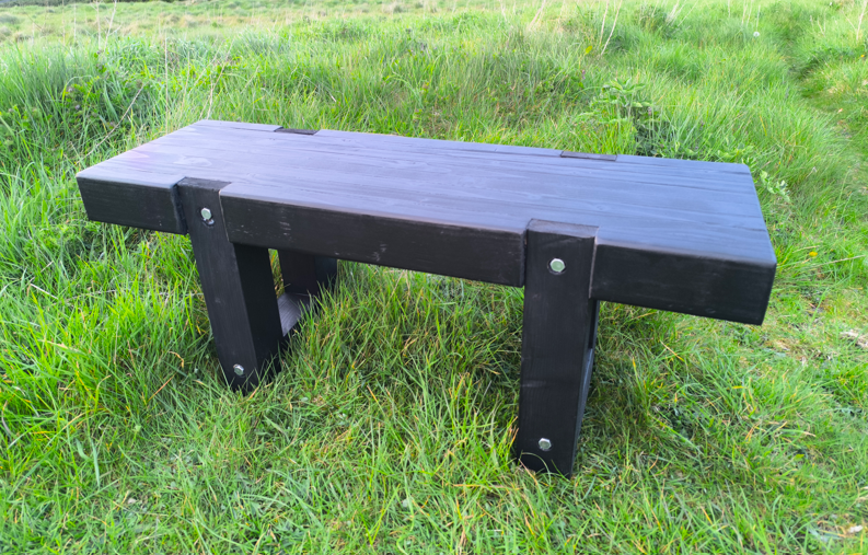 Black wooden bench on grass