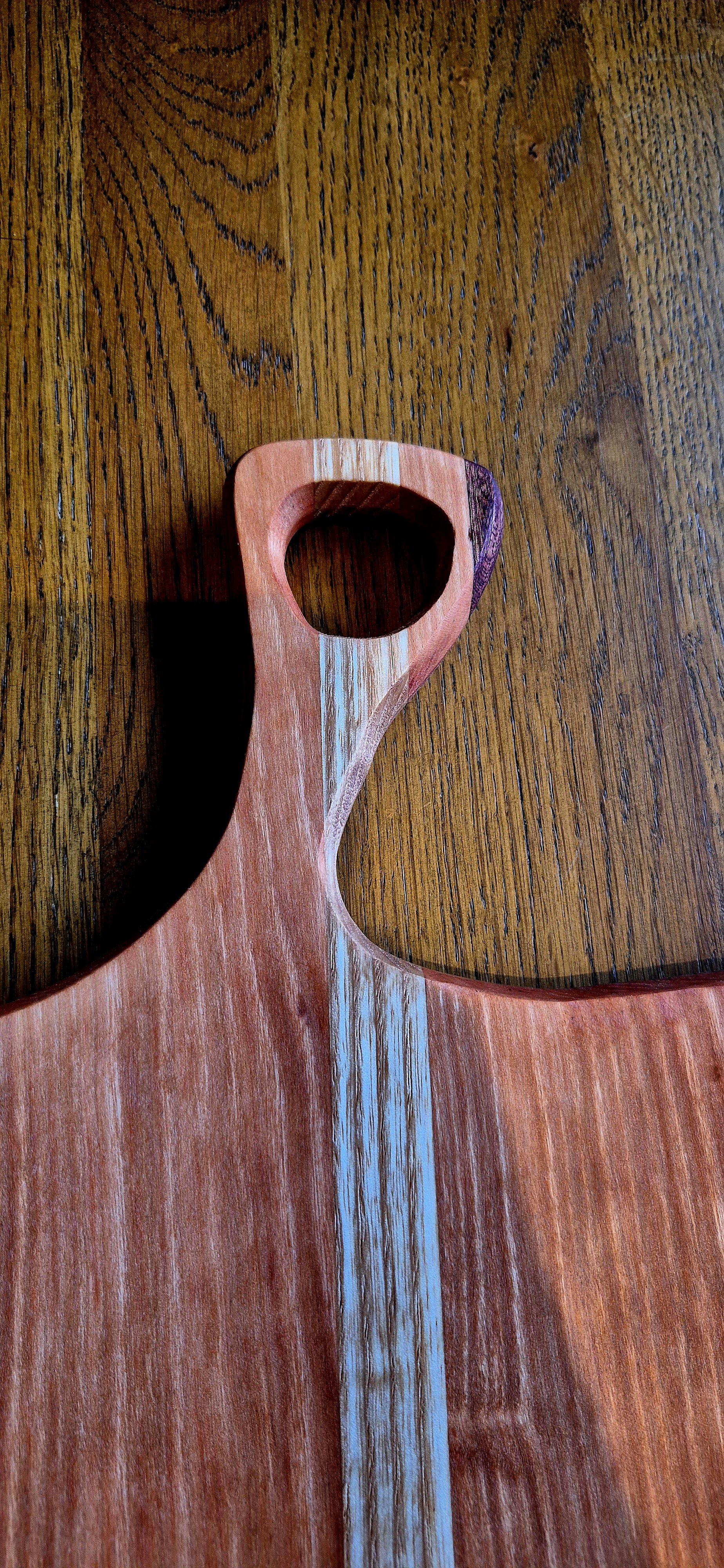 Close-up of the elegant Walnut wood accent on the handle of a Cherry and Oak handcrafted board